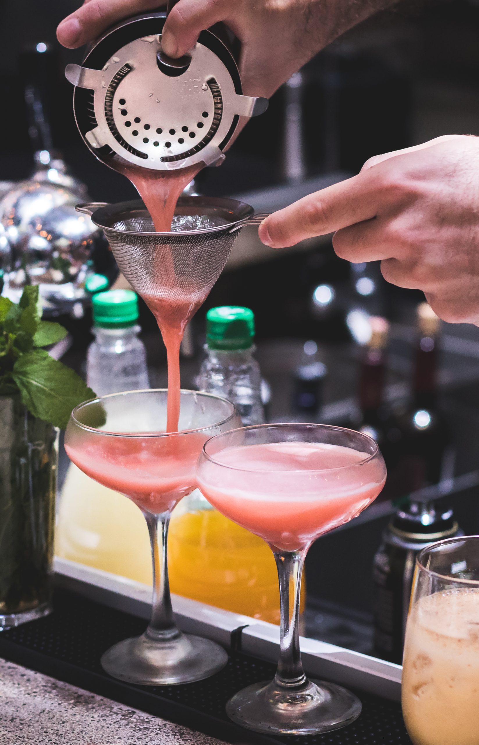 Barman is pouring a pink cocktail via strainer- ברמן מוזג קוקטייל וורוד דרך מסננת לכוס